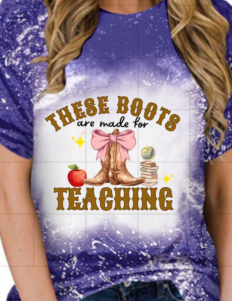 May include: Purple tie-dye t-shirt with the text "These Boots are made for Teaching" in brown lettering. The design features a pair of brown cowboy boots with a pink bow, an apple, and a stack of books.