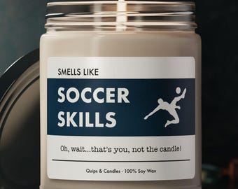 May include: A brown soy wax candle with a white label that reads "SMELLS LIKE SOCCER SKILLS" and "Oh, wait...that's you, not the candle!"  The label also features a silhouette of a soccer player kicking a ball. The candle is in a clear glass jar with a black lid.