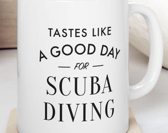 Puede incluir: Taza de cerámica blanca con texto negro que dice "Tastes like a good day for scuba diving".
