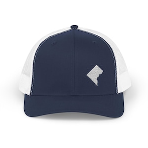 May include: Navy blue and white trucker hat with a white embroidered outline of the District of Columbia. The hat has a mesh back and a curved peak. A stylish accessory for casual wear.