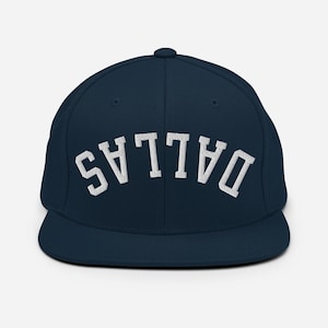 May include: A navy blue baseball cap with the word "DALLAS" embroidered in white, arched across the front. The cap has a flat brim and a button on top. This hat is a classic accessory.