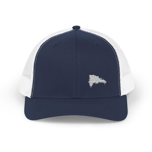 May include: Navy blue trucker hat with a white mesh back and a curved brim. The hat features an embroidered outline of the Dominican Republic in white on the front panel. A classic and stylish accessory.