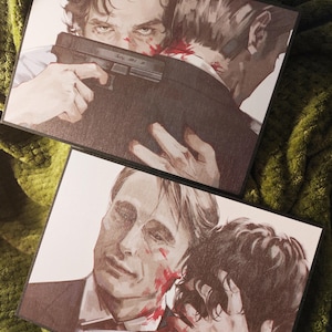 Może przedstawiać: Dwóch mężczyzn, jeden z krwią na twarzy, obejmuje się. Mężczyzna na pierwszym planie ma rękę na ramieniu drugiego mężczyzny. Mężczyzna w tle trzyma pistolet.