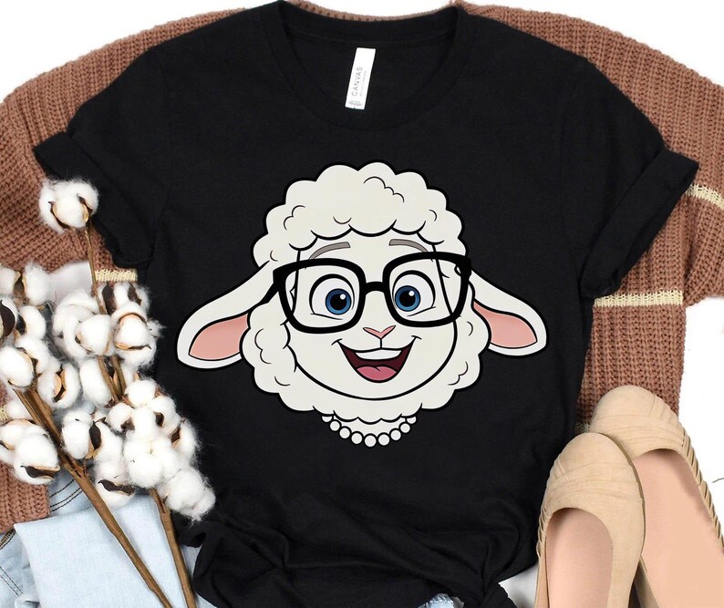 K&ouml;nnte beinhalten: Schwarzes T-Shirt mit einem Cartoon-Schaf mit Brille. Das Schaf hat ein wei&szlig;es Gesicht, blaue Augen und einen l&auml;chelnden Ausdruck. Das T-Shirt besteht aus einem weichen Material und ist f&uuml;r den Freizeitgebrauch geeignet.