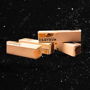 May include: Four small boxes of Bee Beauty Contour makeup stacked on top of each other. The boxes are beige with black text and a small flower graphic.