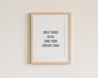 May include: A framed print with a light wood frame and a white mat. The print features the quote "GREAT THINGS NEVER COME FROM COMFORT ZONES" in black text on a white background. The frame is rectangular and hangs on a light beige wall.