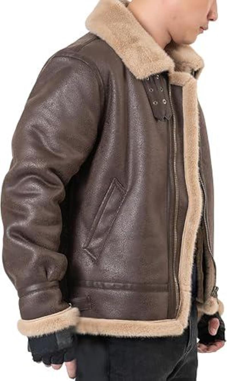 May include: A dark brown jacket with a textured finish, featuring a thick beige faux fur lining and collar. The jacket includes a front metal zipper, two side pockets, and adjustable buckle straps at the collar for a secure fit around the neck.