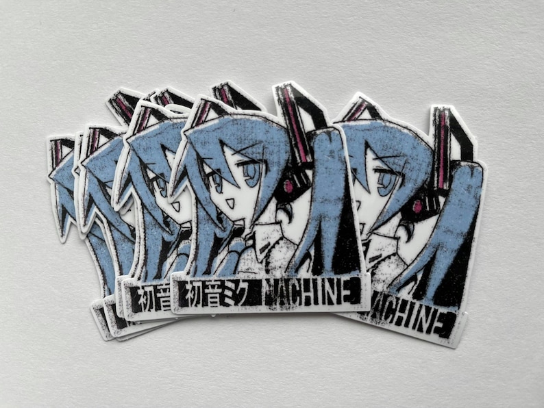 Pu&ograve; includere: Cinque adesivi con un personaggio anime dai capelli blu con un design in bianco e nero. Gli adesivi hanno il testo "初音ミク MACHINE".