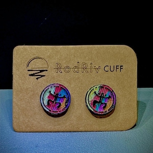 Könnte beinhalten: Ein Paar bunte Holzohrringe mit geometrischem Design. Die Ohrringe werden auf einer braunen Karte mit dem Text "Rod Riv Cuff" präsentiert.