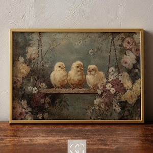 Può includere: Stampa incorniciata con tre soffici pulcini gialli appollaiati su un'altalena di legno. L'opera d'arte ha un'estetica vintage, con colori tenui ed elementi floreali. La cornice è dorata e lo sfondo è blu tenue.