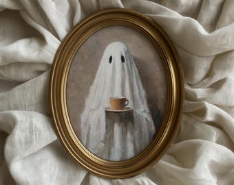 May include: An oval framed painting depicts a ghost figure holding a cup of coffee. The ghost is draped in a white sheet with black eye holes. The cup and saucer are light brown, and the frame is gold.