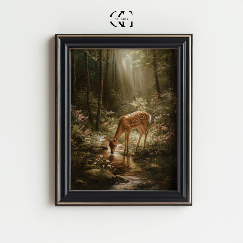 May include: Framed art print featuring a serene forest scene with a deer drinking from a stream. The artwork is set in a black frame with gold trim. The image includes the text "STUDIOS" and the initials "CC".