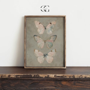 May include: A framed print featuring three delicate butterflies with pastel pink and blue wings on a light gray background.