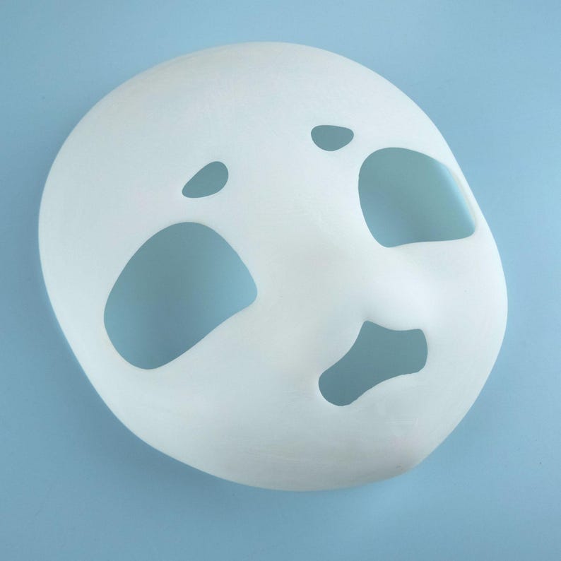 May include: A plain white mask with cut-out eye, nose, and mouth openings. The mask has a smooth, matte finish and is designed to be worn on the face. The mask is likely for costume or theatrical use.