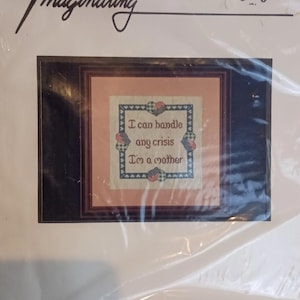 May include: Cross-stitch kit with the word "Imaginating" at the top. The kit features a framed cross-stitch design with the text "I can handle any crisis I'm a mother". The kit is in a clear plastic package.