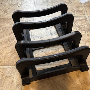 Op de afbeelding: Zwarte kunststof standaard met drie niveaus voor het bewaren van items zoals platen of boeken.