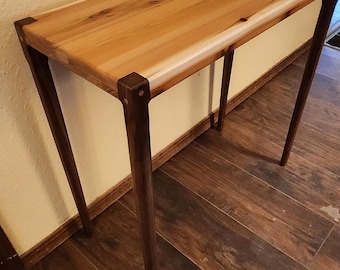 May include: A wooden table with a light brown top and dark brown legs. The table has a simple design with a rectangular top and four legs.