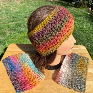 May include: A colorful, crocheted headband and two matching wrist warmers. The headband is on a mannequin head, showcasing a mix of orange, purple, green, and yellow yarn. The wrist warmers display similar color gradients. The items are displayed on a wooden surface.