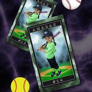 May include: Two rectangular baseball trading cards featuring a child in a green shirt, black trousers, and a black cap holding a bat. The cards display the name AMARAH and the number 14. The background includes a white baseball and a yellow softball.