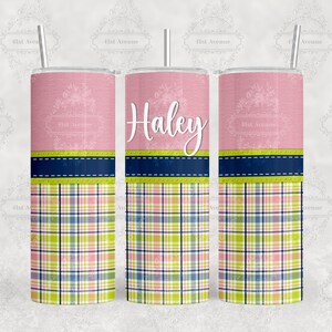 May include: A pink and green plaid tumbler with a pink top and a navy blue and green trim. The tumbler has the name "Haley" printed on it.