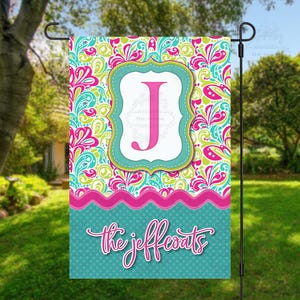 May include: A decorative garden flag with a colorful paisley pattern in pink, green, and teal. It features a white frame with a pink letter "J" and the name "the jeffcoats" in script.