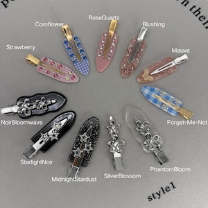 May include: A selection of decorative hair clips in diverse styles. The clips feature embellishments such as rhinestones, floral designs, and patterned elements. Each clip is named, with labels including "Strawberry," "RoseQuartz," and "MidnightStardust."