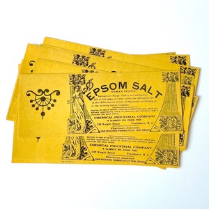 May include: A stack of yellow paper packets with black text and illustrations. The text reads "EPSOM SALT" and "DIRECTIONS: Cathartic to Purge: One or two tablespoonfuls in full glass of water (with one tablespoonful of Our Effervescent Citrate of Magnesia) on retiring or in the morning before breakfast." The text also includes the name "CHEMICAL INDUSTRIAL COMPANY" and the address "139 Knight Street, Providence, R.I."