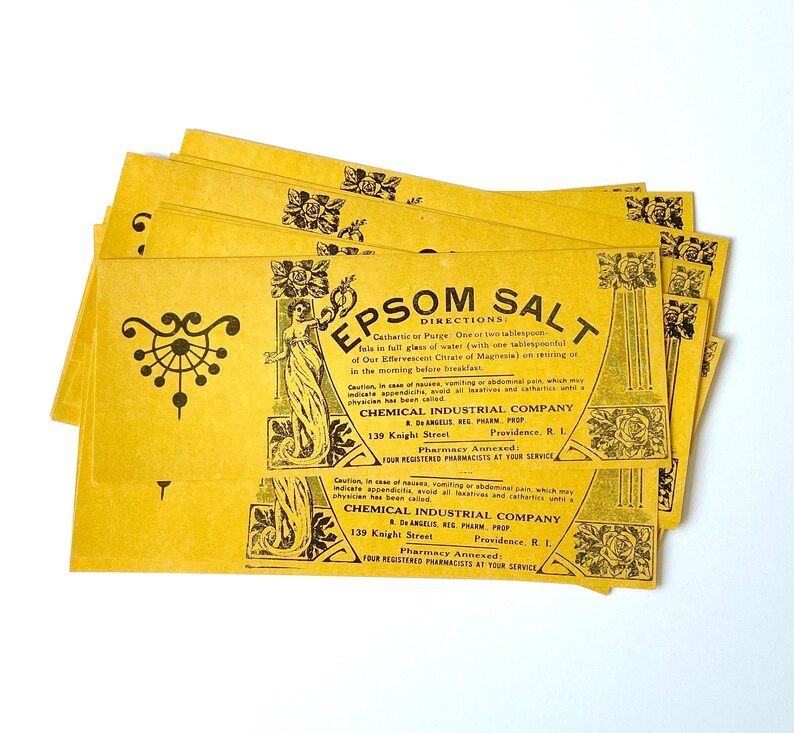 May include: A stack of yellow paper packets with black text and illustrations. The text reads "EPSOM SALT" and "DIRECTIONS: Cathartic to Purge: One or two tablespoonfuls in full glass of water (with one tablespoonful of Our Effervescent Citrate of Magnesia) on retiring or in the morning before breakfast." The text also includes the name "CHEMICAL INDUSTRIAL COMPANY" and the address "139 Knight Street, Providence, R.I."