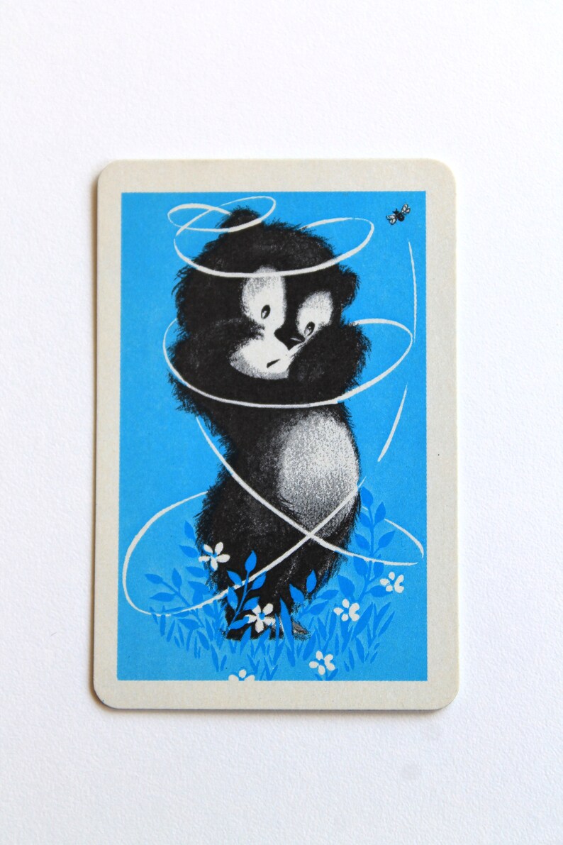 K&ouml;nnte beinhalten: Ein schwarz-wei&szlig;er Comic-B&auml;r vor blauem Hintergrund. Der B&auml;r ist von wei&szlig;en Wirbeln und wei&szlig;en Blumen umgeben. Eine kleine schwarze Biene fliegt in der oberen rechten Ecke.