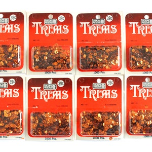 Puede incluir: Ocho paquetes de lentejuelas naranjas, cada uno etiquetado con "Craft House Trims", con un precio de 39 centavos y una cantidad de 1000 piezas.