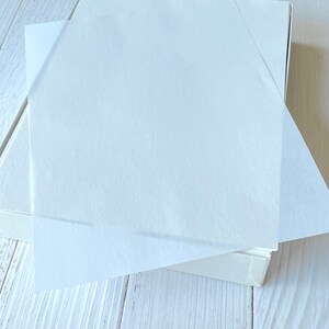Pu&ograve; includere: Una scatola bianca con un mucchio di carta velina bianca all'interno. La carta velina &egrave; leggermente traslucida e ha una consistenza morbida e stropicciata.