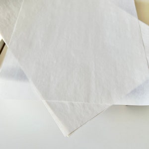 Może przedstawiać: Dwa białe arkusze papieru do pakowania złożone w kształt tr&oacute;jkąta.