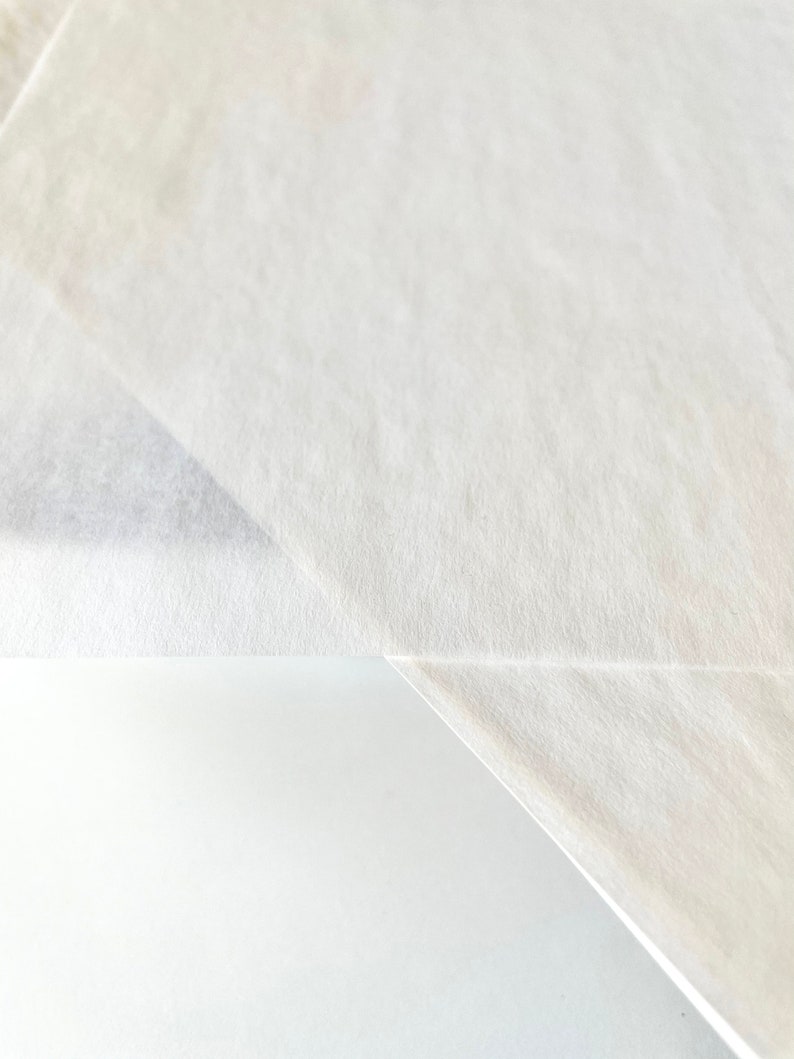 Może przedstawiać: Zbliżenie na białą, teksturowaną powierzchnię papieru. Papier jest złożony na siebie, tworząc ostry zagięcie.