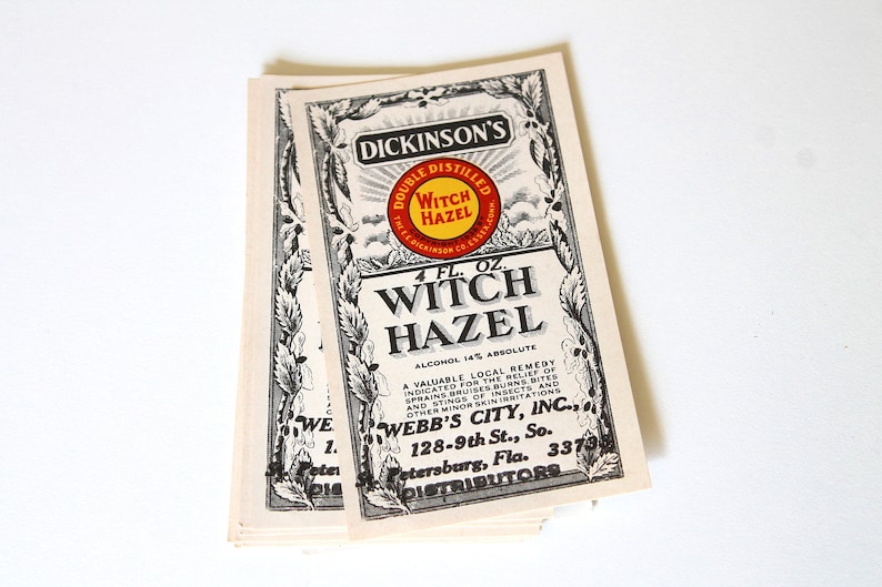 Puede incluir: Una pila de etiquetas vintage de Witch Hazel de Dickinson. Las etiquetas presentan texto negro y bordes decorativos sobre un fondo blanquecino. Las etiquetas incluyen el texto "Double Distilled Witch Hazel" y "4 fl. oz."