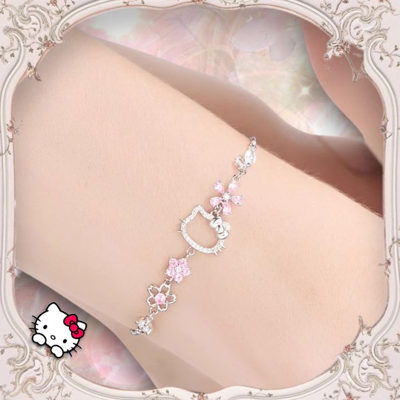 May include: A silver bracelet with a pink Hello Kitty charm and pink flower accents.