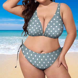 Könnte beinhalten: Ein zweiteiliger Badeanzug in Hellblau, verziert mit weißen Polka-Dots. Das Oberteil hat einen tiefen Ausschnitt und verstellbare Träger, während die Hose einen klassischen Schnitt hat. Der Badeanzug ist für eine bequeme Passform konzipiert.