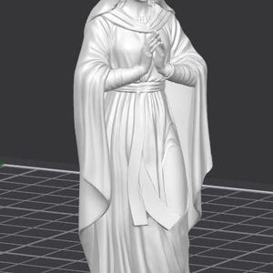 Op de afbeelding: Een wit beeld van een vrouw in een vloeiende jurk en hoofdbedekking, met de handen gevouwen in gebed. De figuur heeft een serene uitdrukking en staat op een oppervlak met een rasterpatroon. Het beeld is een religieuze figuur.