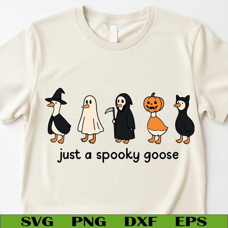 May include: A cream-coloured t-shirt with a Halloween-themed design. It features cartoon geese dressed in costumes: a witch, ghost, grim reaper, pumpkin, and cat. The text "just a spooky goose" is printed below the geese.