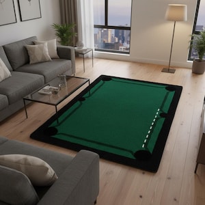 May include: A rectangular green rug designed to resemble a pool table. The rug has black borders and corner pockets, with a white dotted line indicating the cue ball's starting position. The rug is placed on a wooden floor in a living room.
