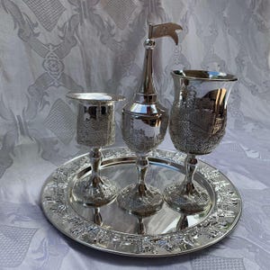 May include: A silver tray with three silver cups and a silver jug. The cups and jug have a design of a city wall with a flag on top of the jug.