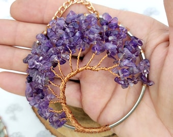 May include: A handcrafted tree of life pendant featuring a copper wire tree with amethyst chips for leaves. The tree is set within a silver-colored ring and suspended from a gold chain.