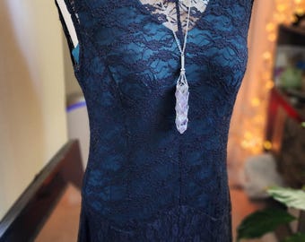 May include: A black lace dress with a silver chain necklace and a purple crystal pendant.