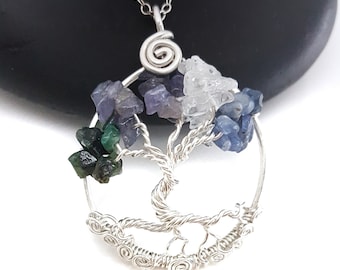 May include: Silver wire wrapped tree of life pendant with green, blue, and purple gemstones. The pendant is on a silver chain.