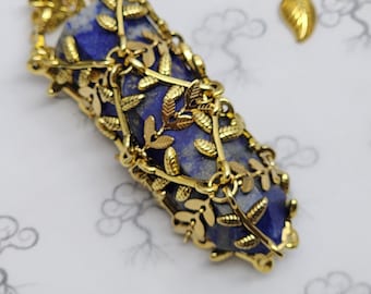 May include: A gold pendant necklace with a blue lapis lazuli stone encased in a gold leaf design.