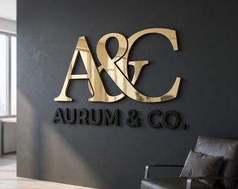 May include: A three-dimensional wall sign featuring the gold metallic letters A&G in a large, stylized serif font, positioned above the black text AURUM & CO. in a clean, sans-serif typeface, mounted on a dark gray wall surface.