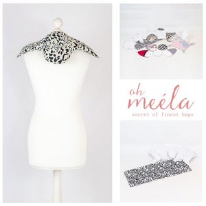 Può includere: Un manichino bianco che indossa un colletto in tessuto con stampa leopardata bianco e nero. Il tessuto è piegato a forma triangolare. Lo sfondo è bianco. Il testo "oh meéla secret of finest bags" è visibile nell'immagine.
