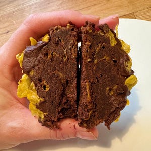 Puede incluir: Un postre de brownie de chocolate con una capa de glaseado de chocolate y cereal triturado en el exterior.