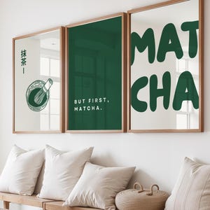 Könnte beinhalten: Drei gerahmte Wandkunstwerke mit Holzrahmen. Der linke Rahmen zeigt japanischen Text und eine Matcha-Quirl-Illustration. Der mittlere Rahmen lautet "BUT FIRST, MATCHA". Der rechte Rahmen zeigt "MAT CHA" in großen grünen Buchstaben.