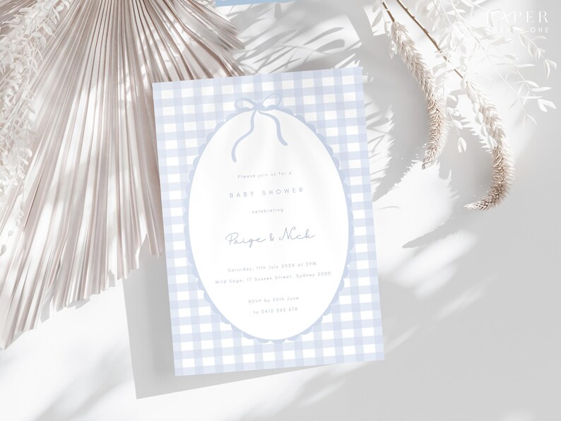 Pu&ograve; includere: Invito per baby shower con sfondo a motivo gingham azzurro chiaro. L'invito presenta una forma ovale con un disegno a fiocco nella parte superiore. Il testo recita "Baby Shower" e i nomi "Paige & Nick".