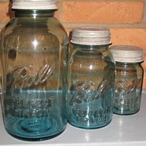 May include: Three glass Ball brand mason jars with silver lids. The largest jar is blue and says 'Perfect Mason' on the side. The middle jar is blue and says 'Perfect Mason' on the side. The smallest jar is blue and says 'Perfect Mason' on the side.